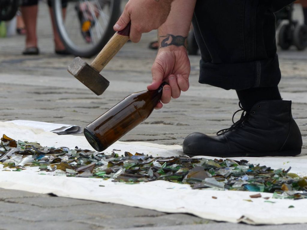 A busker breaking glass during a street show