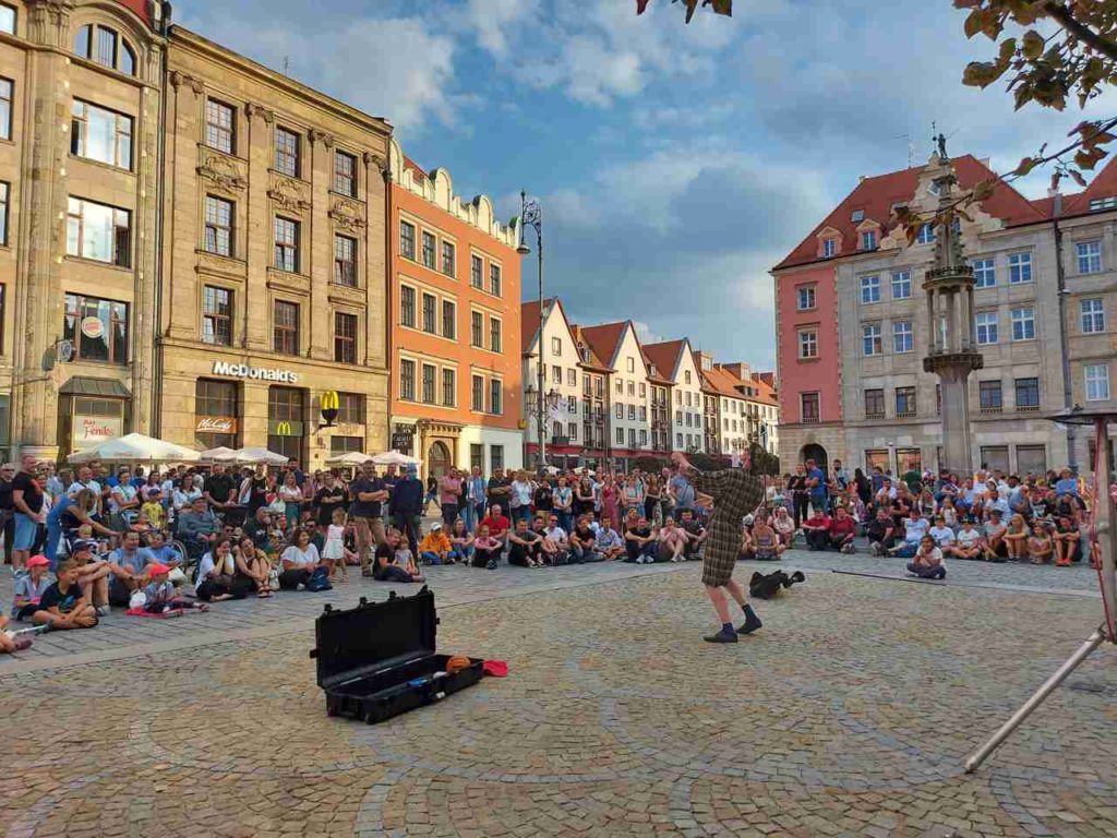 The crowd in the market square in Wroclaw watches a performer Sam Goodburn. He wears a bathrope.