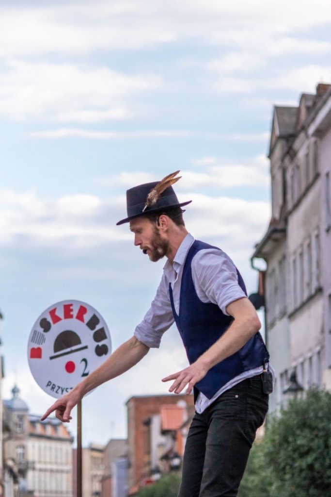 Street performer Richard performing next to the BuskerBus festival sign