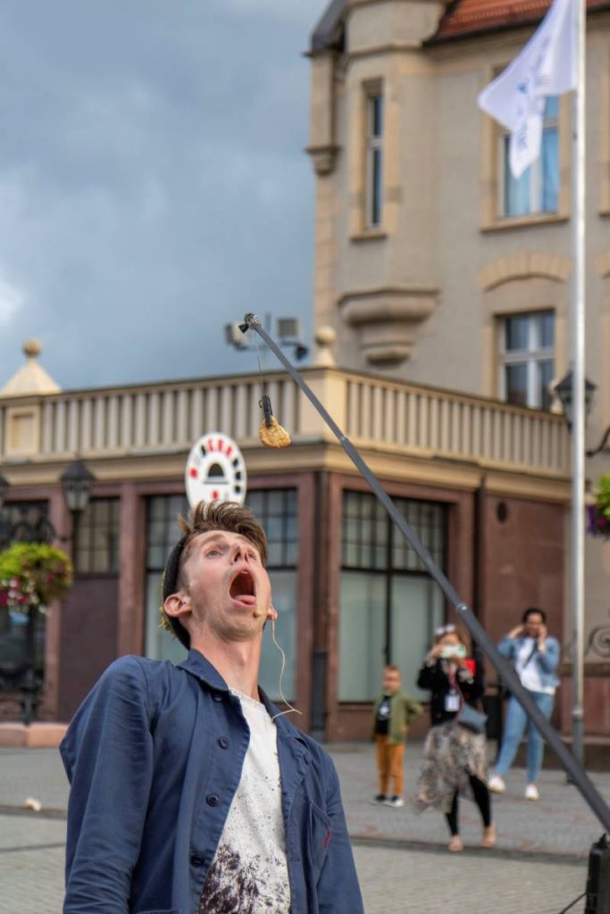 Sam Goodburn and his cookie act at BuskerBus 2021. He tries to reach a cookie attached to a fishing rod.