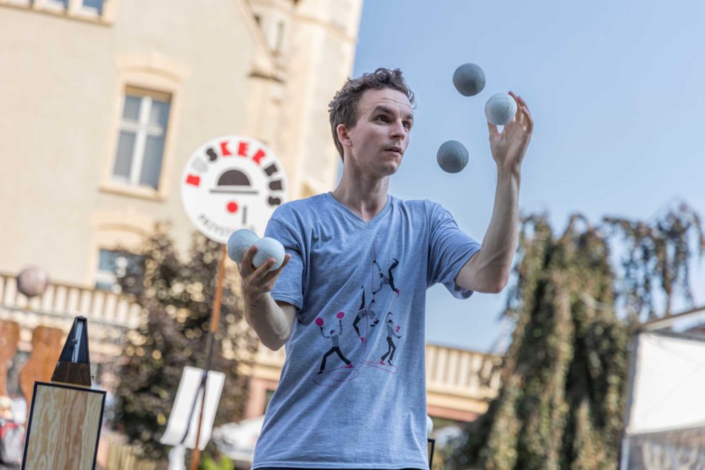 Artysta uliczny Domeny La Terra żongluje pięcioma piłkami