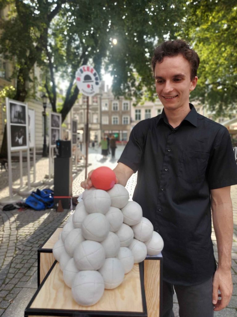 Domenyk La Terra stands behind the juggling balls formed in a shape of pyramid