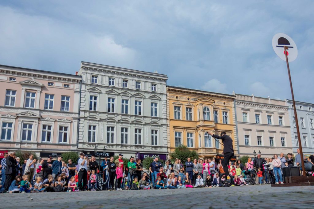 Publiczność na Rynku w Krotoszynie ogląda występ uliczny artysty cyrkowego na monocyklu 