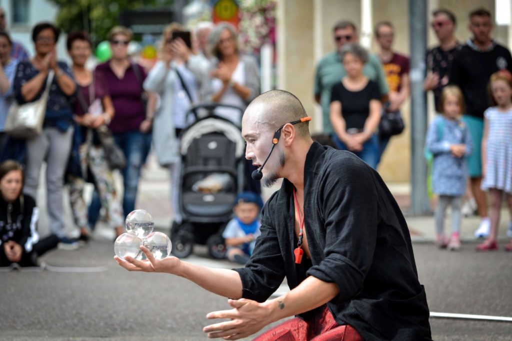 Performer Monk trzyma w ręce kilka kryształowych kul do manipulacji. 