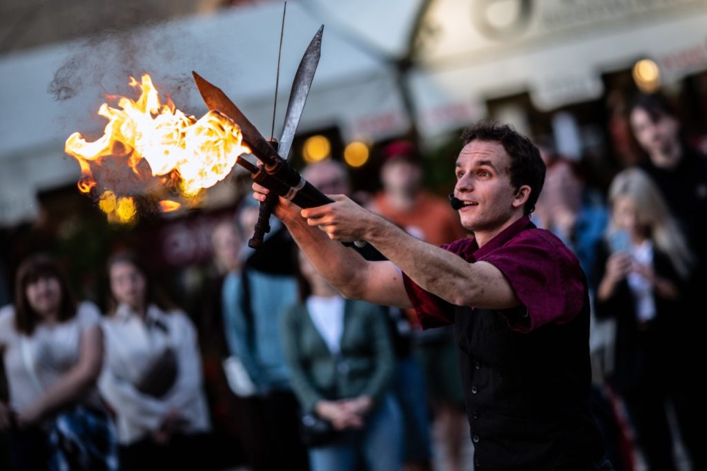 Busker Tour – artysta Juggling Dom fot. Tobiasz Papuczys Artysta uliczny Juggling Dom trzyma w rękach maczety i płonącą pochodnię
