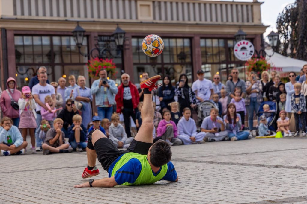 Stefan Florescu freestyle football na festiwalu Busker Tour w Krotoszynie fot. Joanna Dryjańska-Pluta Performer uliczny wykonuje triki footbalowe na Rynku w Krotoszynie na festiwalu ulicznym Busker Tour