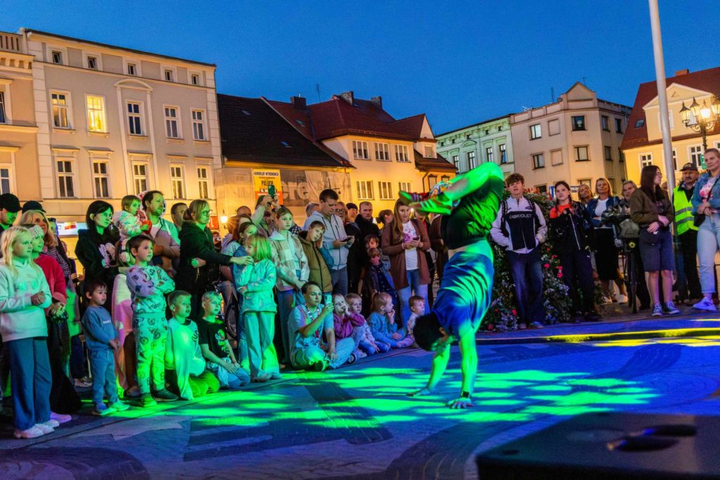 Stefan Florescu performing a handstand in front of an audience watching his street show at the Krotoszyn market square during Busker Tour.